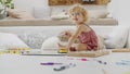 Smiling child, beautiful little girl with blue eyes and curly blonde hair, draws and writes cheerfully playing with coloured pens Royalty Free Stock Photo