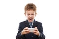 Smiling child boy in business suit playing games or surfing internet on smartphone computer Royalty Free Stock Photo