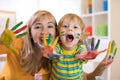 Smiling child boy and his mother having fun and showing hands painted in colorful paints Royalty Free Stock Photo