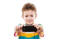 Smiling child boy holding mobile phone or smartphone taking self Royalty Free Stock Photo