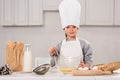 smiling child in chef hat whisking eggs in bowl at table Royalty Free Stock Photo