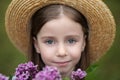 Smiling child girl with big eyes looking in camera. Closeup portrait of a romantic charming little girl in straw hat. Childhood co
