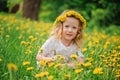 Smiling child girl in dandelion wreath on spring flower field Royalty Free Stock Photo