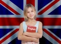 Smiling child girl holding english book against UK flag background. Learn English language concept Royalty Free Stock Photo