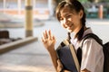 Smiling child girl of primary school carrying backpack on her back and books in hand going to school,schoolgirl raise her right Royalty Free Stock Photo