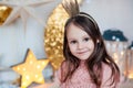 Smiling child girl wearing golden crown posing against christmas decorations. Royalty Free Stock Photo