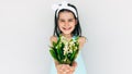 Smiling child holding the bouquet of white flowers giving it to her mother. Cute kid holding a bouquet in front of her face