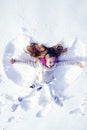 Smiling child lying on snow with copy space. Funny kid making snow angel. Child girl playing and making a snow angel in Royalty Free Stock Photo