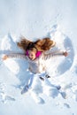 Smiling child lying on snow with copy space. Funny kid making snow angel. Child girl playing and making a snow angel in Royalty Free Stock Photo