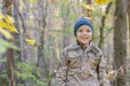 Smiling child playing with fallen autumn leaves. Boy holding bunch of maple leaves in the forest Royalty Free Stock Photo