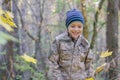 Smiling child playing with fallen autumn leaves. Boy holding bunch of maple leaves in the forest Royalty Free Stock Photo