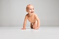 Smiling child. Portrait of little cute toddler boy, baby in diaper crawling isolated over gray studio background Royalty Free Stock Photo