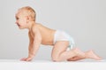 Smiling child. Portrait of little cute toddler boy, baby in diaper crawling isolated over gray studio background Royalty Free Stock Photo