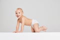 Smiling child. Portrait of little cute toddler boy, baby in diaper crawling isolated over gray studio background Royalty Free Stock Photo