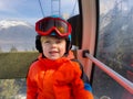 Smiling child sit in ski lift with mountain view on the back Royalty Free Stock Photo