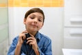 Smiling child sprays cologne on his neck while looking at the camera