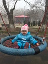 Smiling child on a swing in a foggy park.