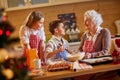 Smiling children and grandmother preparing Xmas cookies