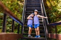 Smiling children in striped t-shirts, blue shorts and hats stand hugging on the steps in summer