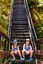 Smiling children in summer Panama and shorts sit on the steps in summer. Vertical photo