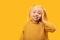 Smiling children talking on phone. Little blond girl use of smartphones. Portrait on yellow background. Copy space, mock up Royalty Free Stock Photo