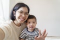 Smiling Chinese mother and her little cute boy making video call on using smartphone at home, Asian family taking selfie on mobile Royalty Free Stock Photo