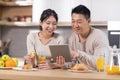 Smiling chinese spouses having breakfast and using tablet Royalty Free Stock Photo