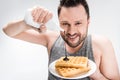 Chubby man pouring chocolate syrup on waffles on white