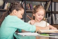 Smiling classmates doing homework together in library