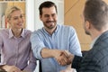 Smiling clients shaking hands with male real estate agent indoors. Royalty Free Stock Photo