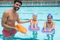 Smiling coach assisting a kids in swimming in pool