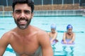 Smiling coach sitting near poolside