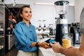 Smiling coffee shop owner holding POS terminal