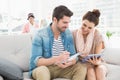 Smiling colleagues using tablet and taking notes on couch Royalty Free Stock Photo