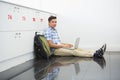 Smiling college student sitting on the floor with laptop