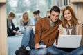 Smiling college students with laptop in library