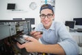 Smiling computer engineer working on broken console with screwdriver Royalty Free Stock Photo