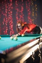 Smiling concentrated ginger woman playing billiard in nice architected club