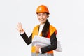 Smiling confident asian female engineer, construction manager in safety helmet, carry blueprints, showing four fingers Royalty Free Stock Photo