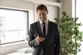 Smiling confident businessman wearing suit looking at phone screen Royalty Free Stock Photo