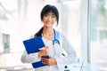 Smiling confident female doctor holding clipboard posing in hospital Royalty Free Stock Photo