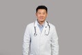 Smiling confident handsome mature chinese man therapist in white coat with stethoscope