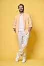 Smiling confident indian man standing isolated on yellow. Vertical full length