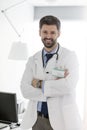 Smiling confident mid adult doctor standing with arms crossed at hospital