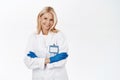 Smiling confident woman doctor, professional standing with arms crossed, wears medical gloves and clinic uniform, white Royalty Free Stock Photo