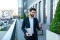 Smiling confident young businessman with beard in suit with laptop typing on smartphone Royalty Free Stock Photo