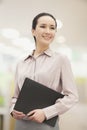 Smiling confident young woman holding a file indoors, looking away Royalty Free Stock Photo