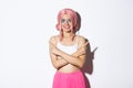 Smiling confident young woman in party costume and pink wig looking satisfied, pointing fingers sideways, showing left Royalty Free Stock Photo
