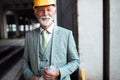 Smiling construction manager, engineer, businessman, architect standing on construction site