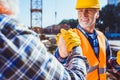 Smiling construction worker in protective uniform shaking hands